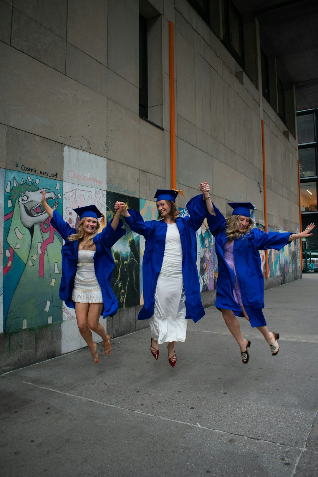 Diverse group of young graduates jumping outdoors celebrating success
